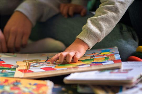 Eine Kinderhand zeigt auf ein Buch.