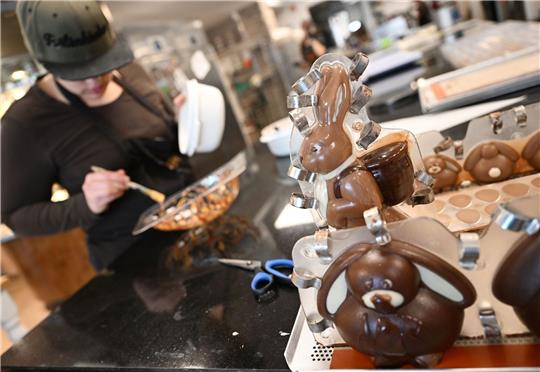 Eine Konditorin «schminkt» in der Chocolaterie Amelie in Garmisch-Partenkirchen eine Osterei-Form.