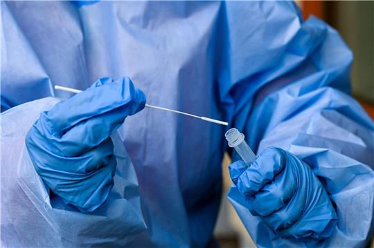 Eine Krankenschwester steckt ein Abstrichstäbchen in die Flüssigkeit eines Corona-Schnelltests.