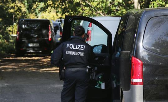 Eine Kriminaltechnikerin steht in der Nähe vom S-Bahnhof Hohenschönhausen neben Fahrzeugen der Polizei. Die Bahn wurde Opfer eines gezielten Angriffs.