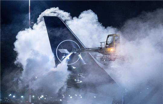 Eine Lufthansa-Maschine wird auf dem Flughafen Frankfurt enteist. Angesichts der Wetterlage hat der Flughafen den Flugplan zusammengestrichen.