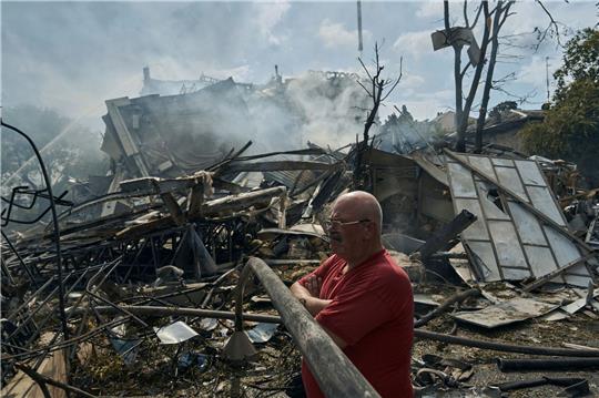 Eine Mann sieht zu, wie Rettungskräfte nach einem Angriff auf die südukrainische Region Odessa an einem zerstörten Gebäude arbeiten.