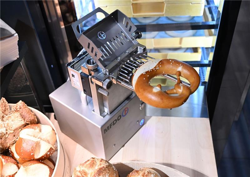 Tüftler wollen Butterbrezel mit Maschine revolutionieren Eine Maschine befüllt in einer Bäckerei eine Brezel mit Butter.