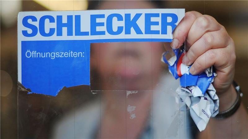 Schlecker-Insolvenz: Millionen-Klage wird neu geprüft Eine Mitarbeiterin der Drogeriemarktkette Schlecker reißt das Firmenlogo von der Eingangstür einer Filiale.