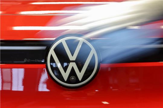Eine Mitarbeiterin wischt über das VW-Logo an einem ID.4.