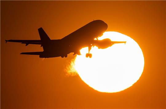Eine Passagiermaschine hebt vor der untergehenden Sonne vom Flughafen Frankfurt ab.