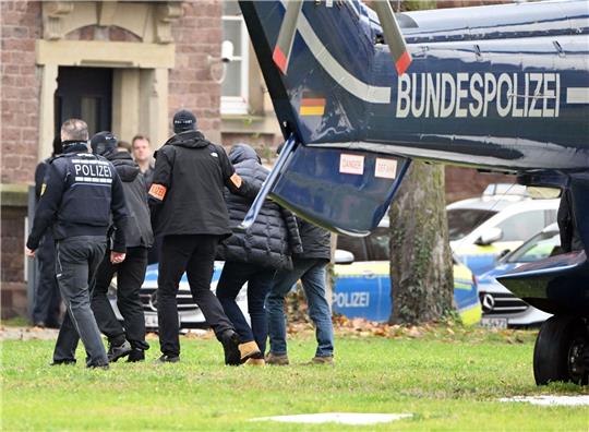 Eine Person (2.v.r.) wird von Polizisten aus einem Hubschrauber gebracht.