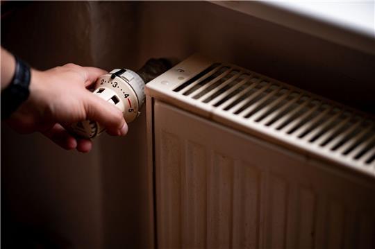 Eine Person benutzt einen alten Heizkörper in einer Berliner Altbauwohnung.