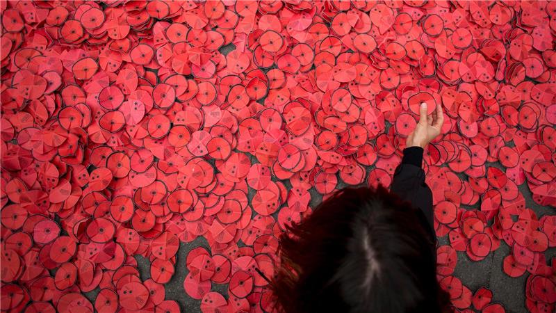 Bilder des Tages Eine Person hebt eine Papiermohnblume auf, die während einer Kundgebung gegen den Gaza-Krieg vor dem spanischen Außenministerium in Madrid auf dem Boden liegt.
