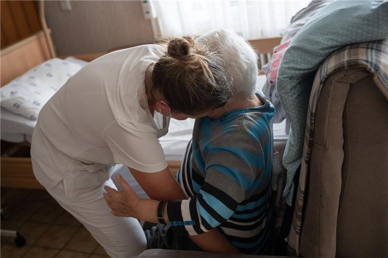 Eine Pflegefachkraft hilft in der ambulanten Pflege einer Frau beim Umsetzen.