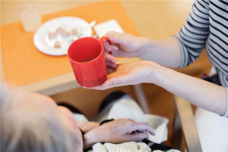 Pflegereform: Linke will nur noch gemeinnützige Träger Eine Pflegerin reicht einer Frau ein Getränk.