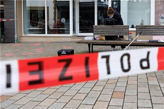 Eine Polizeibeamtin der Kriminaltechnik steht an einem abgesperrten Tatort.