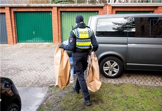 Eine Polizistin trägt Beweismittel aus einem Mehrfamilienhaus. Eine Hundertjährige soll dort von ihrem Enkel getötet worden sein.