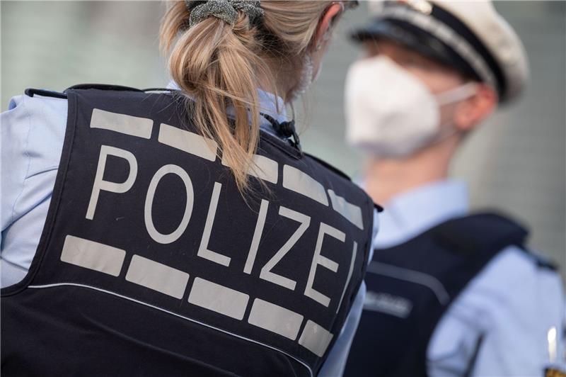 Eine Polizistin und ein Polizist mit FFP2-Maske stehen sich gegenüber.