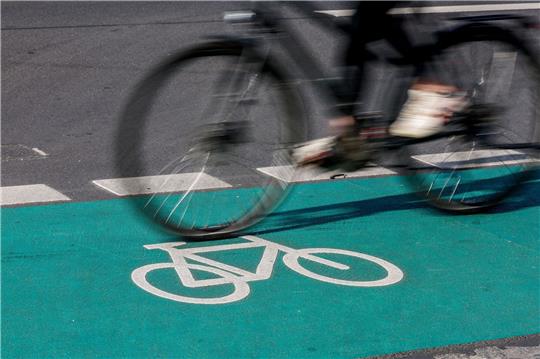 Eine Radfahrerin fährt in Leipzig über einen grün eingefärbten Radweg.