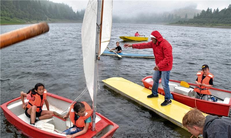 Eine Regenfront ereilt die Ferien-Segler. Jetzt heißt es schnell Festmachen: Lothar König wartet mit dem Bootshaken auf dem Steg, um den Kindern beim Anlegen zu helfen. Foto: Neumann