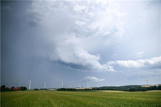 Eine Regenfront mit dunklen Wolken ist hinter einem Gerstenfeld zu sehen.