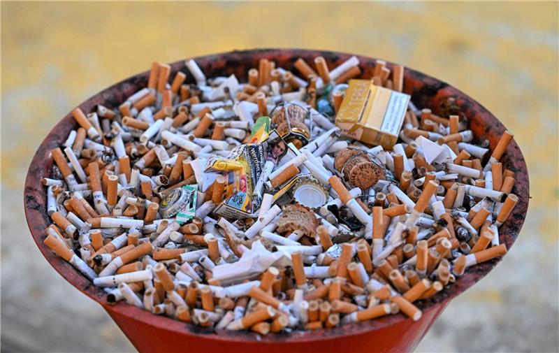 Absatz von Tabakwaren 2023 erneut rückläufig Eine Schale voller Kippen und Zigarettenschachteln.