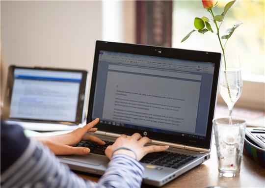 Eine Schülerin erledigt Schulaufgaben an einem Laptop.