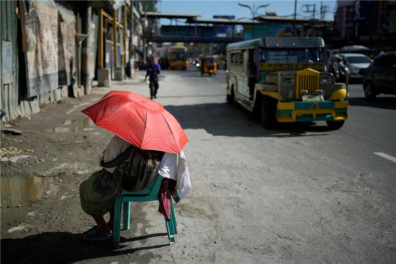 Extremhitze auf den Philippinen - Schulen schließen Eine Straßenverkäuferin schützt sich in Manila mit einem Regenschirm vor der Sonne.