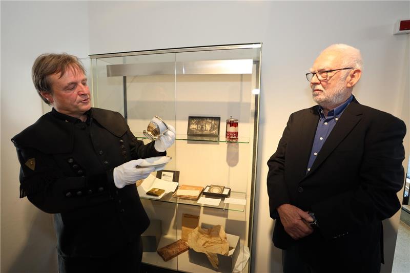 Zwei Männer stehen nebeneinander, einer hält eine Tasse in der Hand.