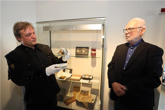 Zwei Männer stehen nebeneinander, einer hält eine Tasse in der Hand.