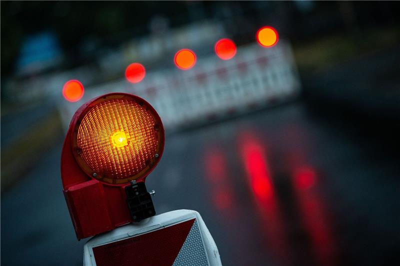 Eine Warnleuchte steht an einem abgesperrten Bereich auf einer Straße.