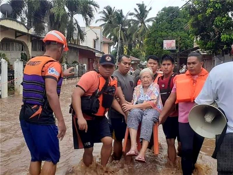Mindestens 25 Tote nach starkem Regen auf den Philippinen Eine ältere Frau wird von Mitarbeitern der Küstenwache in Sicherheit gebracht.