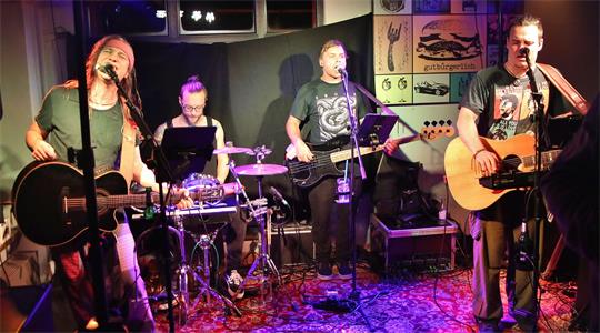 Das Bild zeigt eine Band, die in einer Kneipe spielt.
