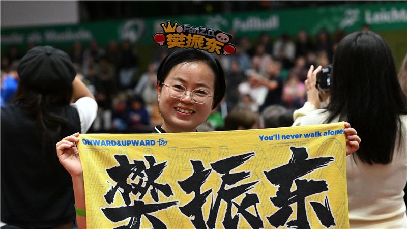 Hype um Tischtennis-Star: Fans aus China heiß auf Bundesliga Eine chinesische Anhängerin hält beim Bundesliga-Spiel zwischen Werder Bremen und dem 1. FC Saarbrücken ein chinesisches Fanplakat hoch.