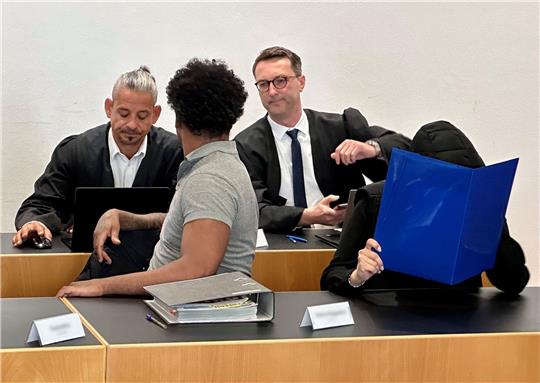 Eine ehemalige Justizvollzugsbeamtin (vorn r) und ein Häftling der Justizvollzugsanstalt Kaisheim (vorn l) sitzen auf der Anklagebank im Strafjustizzentrum Augsburg, im Hintergrund die Verteidiger Marco Müller (l) und Patrick Schmidt.
