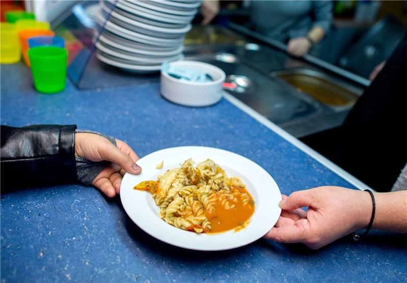 Eine ehrenamtliche Mitarbeiterin verteilt in der Mensa der Grundschule Mühlenberg in Hannover das Mittagsgericht.