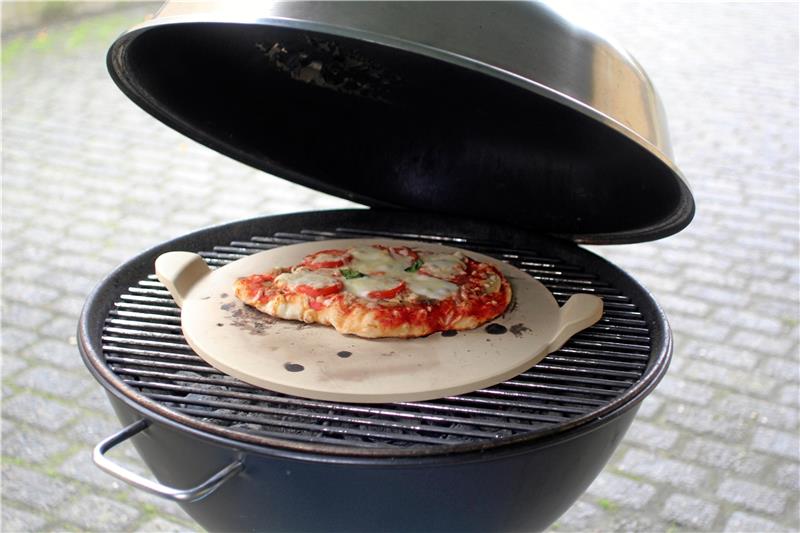 Wenn Kinder in Bad Harzburg zu Pizzabäckern werden Eine fertige Pizza auf einem Pizzastein, der auf dem Grill liegt. Foto: Jenzora