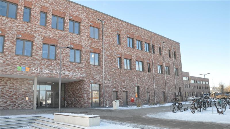 Backsteinbau mit mehreren Fenstern und Fahrradständern vor dem Eingang bei klarem Himmel