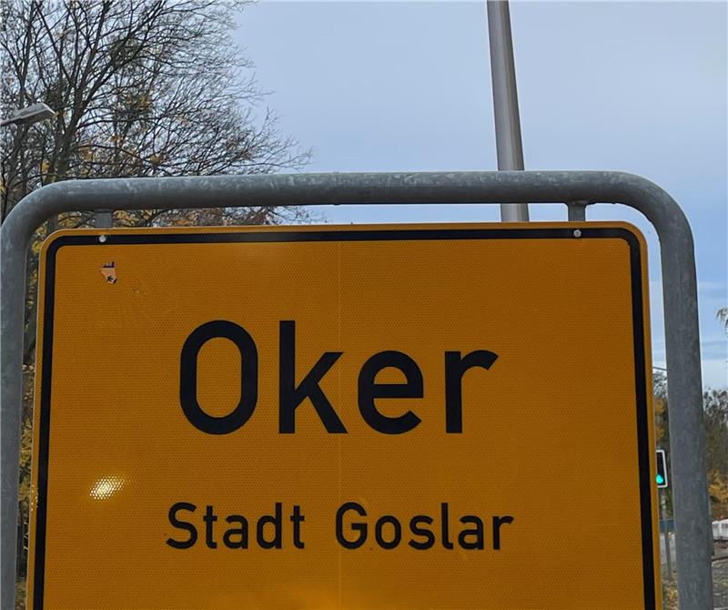Gelbes Ortsschild mit schwarzer Aufschrift 'Oker - Stadt Goslar' an einem Metallrahmen 
