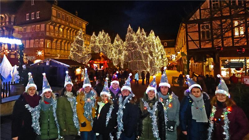 Mehrere Frauen mit leuchtenden Weihnachtsmützen und blinkenden Schals stehen auf dem Goslarer Weihnachtsmarkt.