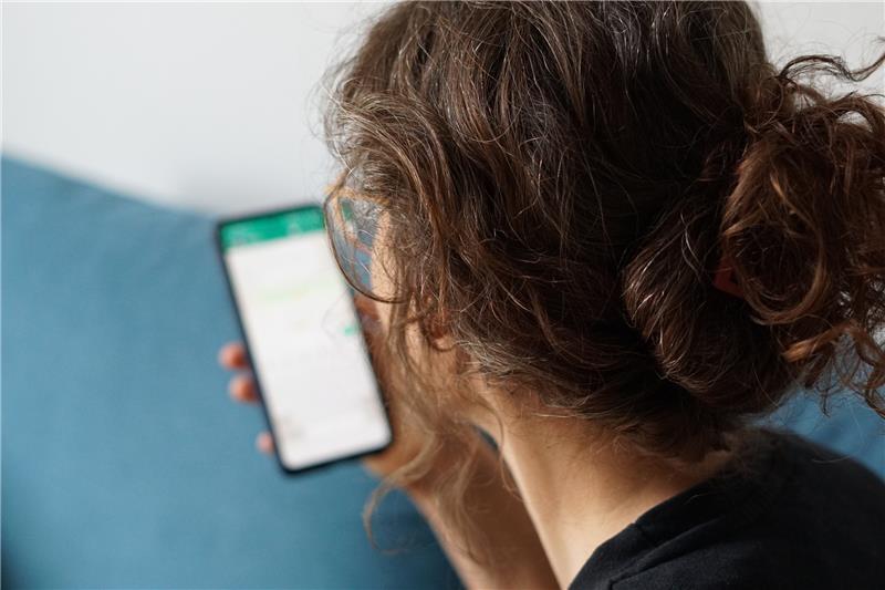 Ghosting: Wenn sich eine Bekanntschaft in Luft auflöst Eine junge Frau hält ihr Smartphone in der Hand und liest eine Whatsapp-Nachricht. Foto: Weronika Peneshko/dpa