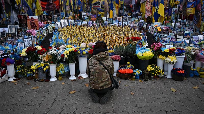 Eine junge Frau kniet am Unabhängigkeitsplatz Maidan in Kiew. Hier wird den Gefallenen des Krieges gedacht.