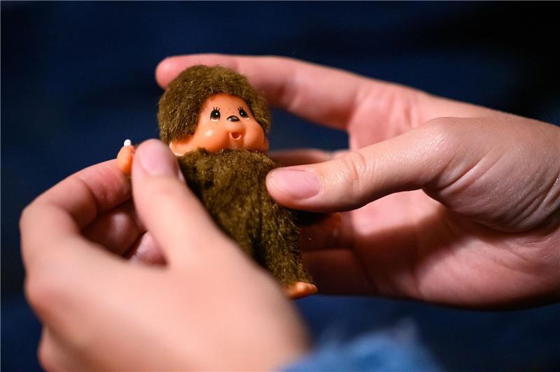 Eine junge Frau spielt mit einem Monchichi.