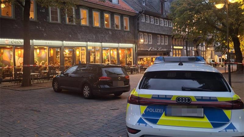 Ein schwarzes und ein Polizeiauto stehen in der Fußgängerzone.