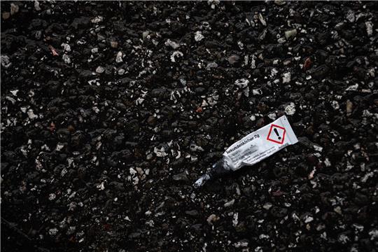 Eine leere Tube Sekundenkleber liegt an der Fahrbahn. Symbolbild: picture alliance/dpa | Christian Charisius
