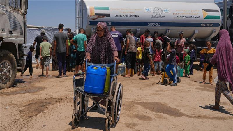 Eine palästinensische Frau schiebt einen Rollstuhl mit Plastikkanistern mit Wasser im Gazastreifen.