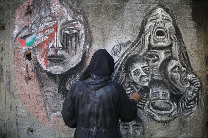 Netanjahu: Kein neuer Vorschlag von Hamas für Geisel-Deal Eine palästinensische Künstlerin bemalt mit Kohle die Wände einer Schule in Deir al-Balah im Zentrum des Gazastreifens, in die sie umgesiedelt wurde.