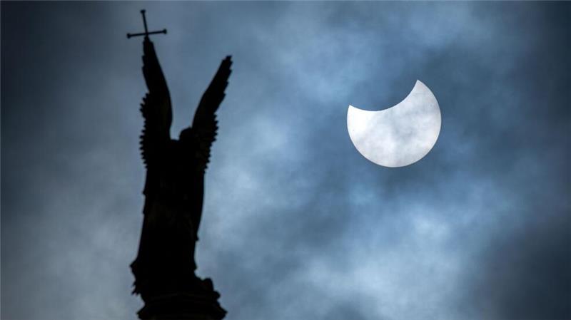 Sonne, Mond und Sterne im März - Mond- und Sonnenfinsternis Eine partielle Sonnenfinsternis über der Statue des Erzengel Michael auf der Kuppel des Schweriner Schlosses.