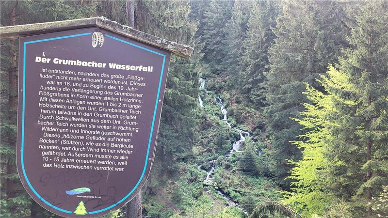 Ein braunes Schild mit der Geschichte zum Grumbacher Wasserfall.