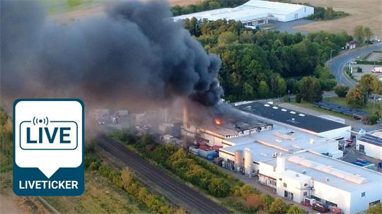 Eine dunkle Rauchwolke über eine Industriehalle.
