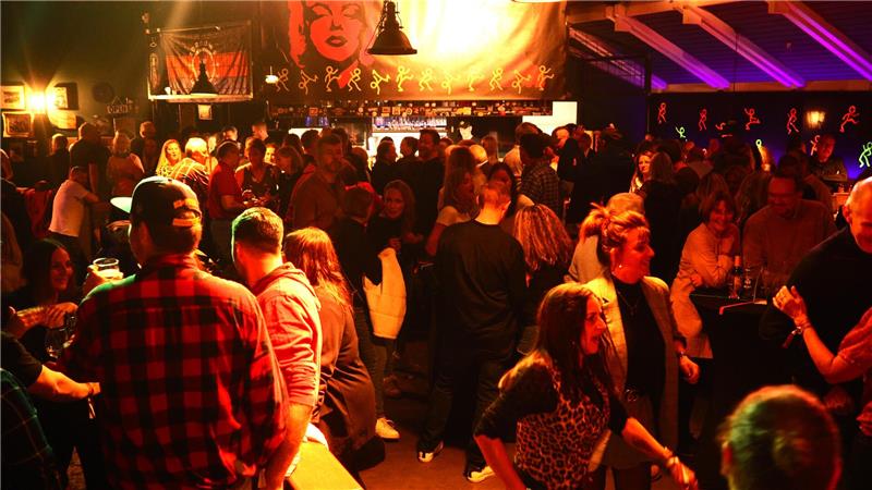 Viele Menschen feiern und tanzen im Partylicht.