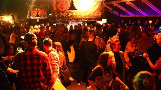 Viele Menschen feiern und tanzen im Partylicht.