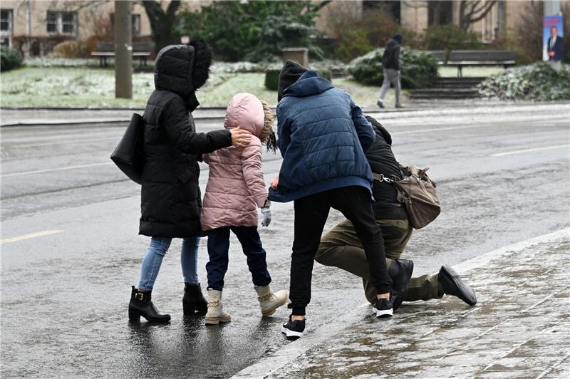 Glatteis: So schlitterte Niedersachsen in den Montag Einem Mann, der bei Eisglätte vom Gehweg auf die Straße gestürzt ist, wird aufgeholfen. Symbolbild: Uwe Zucchi/dpa
