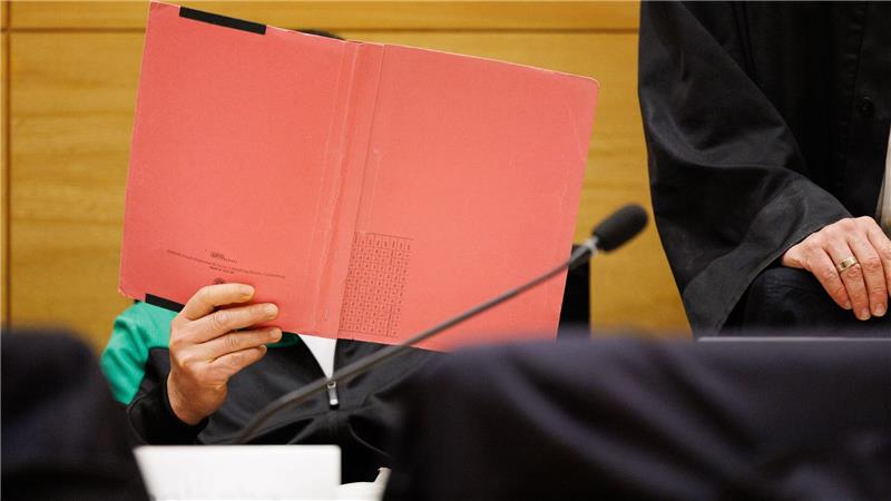 Einer der Angeklagten am Landgericht Bielefeld sitzt neben seinem Verteidiger und verdeckt sein Gesicht.